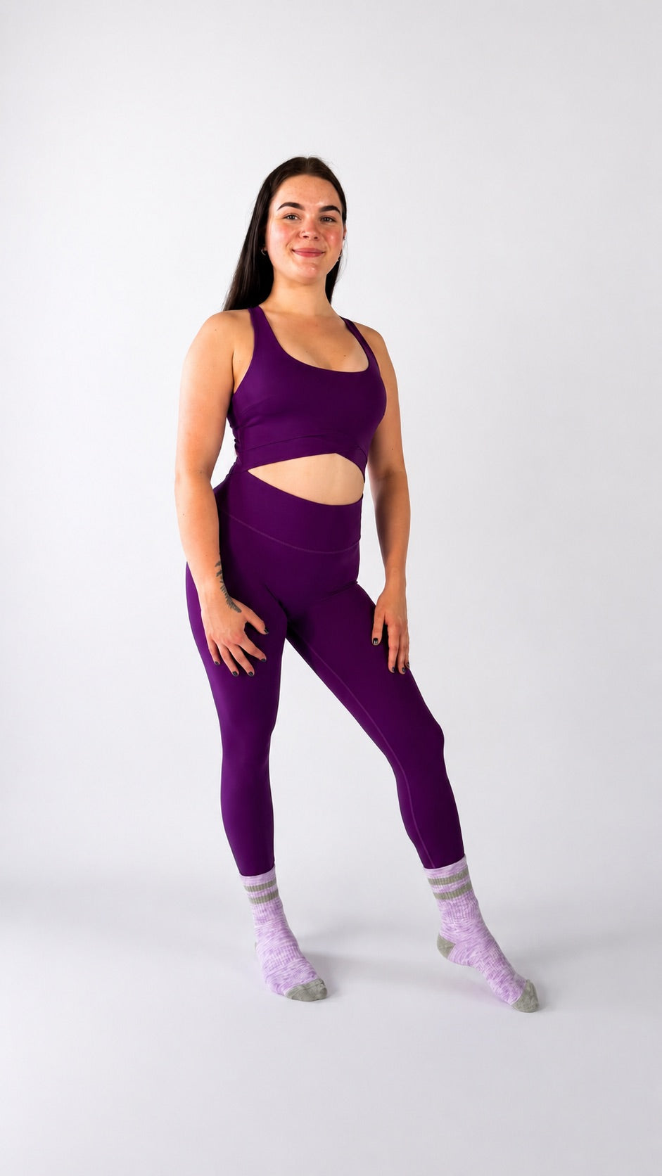 A model showcasing the Luna Jumpsuit in vibrant purple, highlighting its stylish design and activewear functionality.